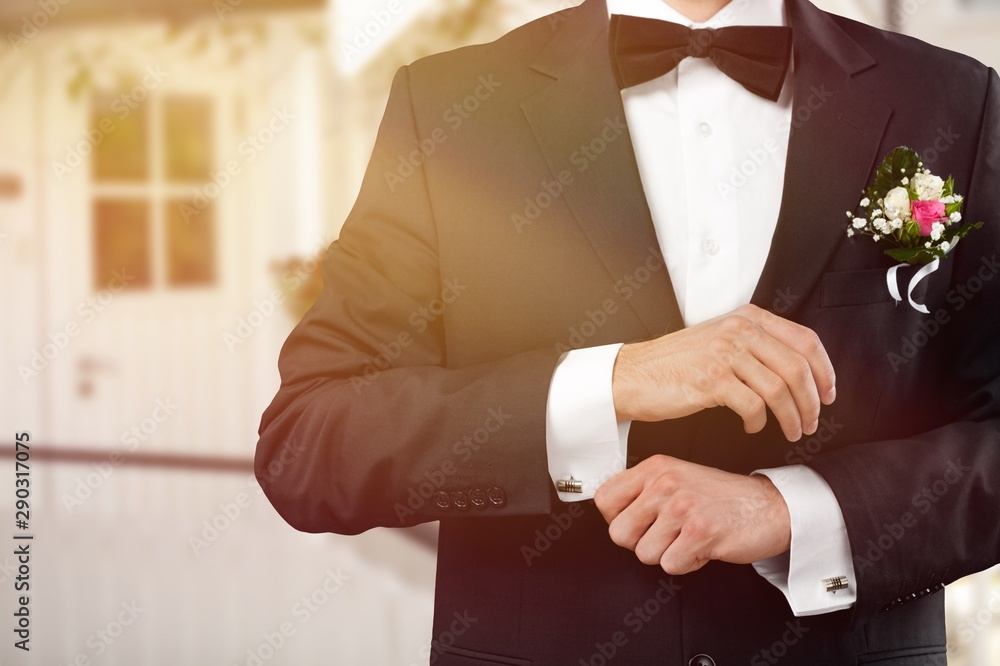 Male groom in wedding suit with bow tie on black