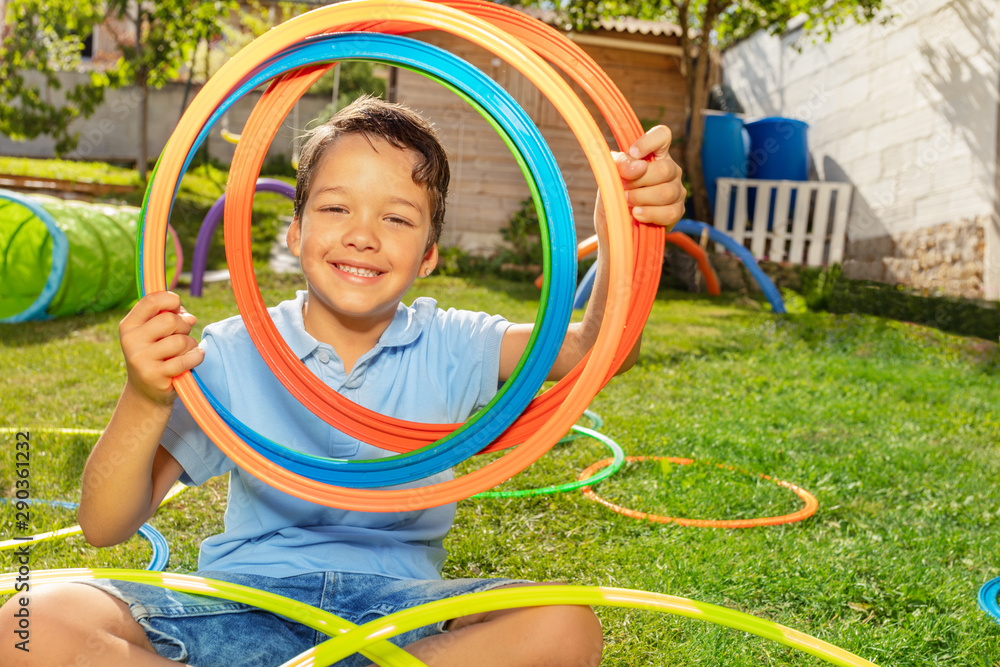 Happy boy portrait through color rings in garden