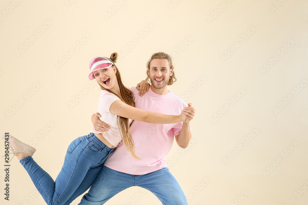 Cool young couple dancing against light background