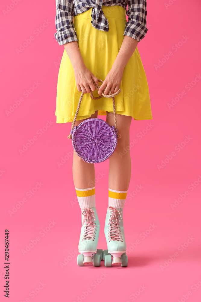 Beautiful young woman on roller skates against color background