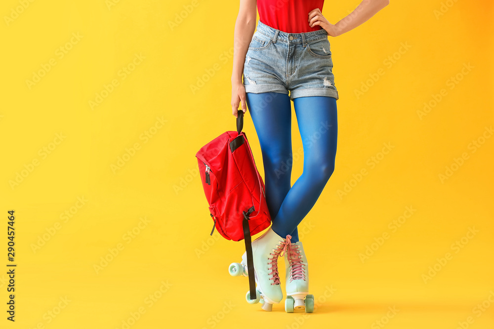 Beautiful young woman on roller skates against color background