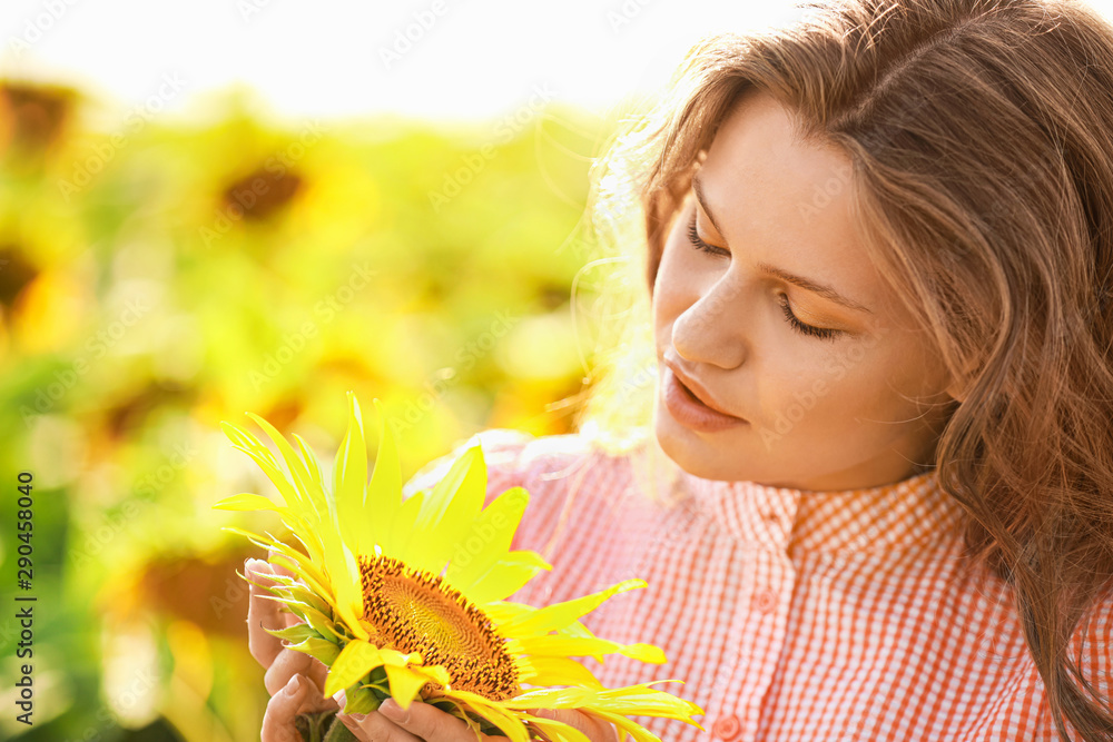 Beautiful young woman in sunflower field on summer day