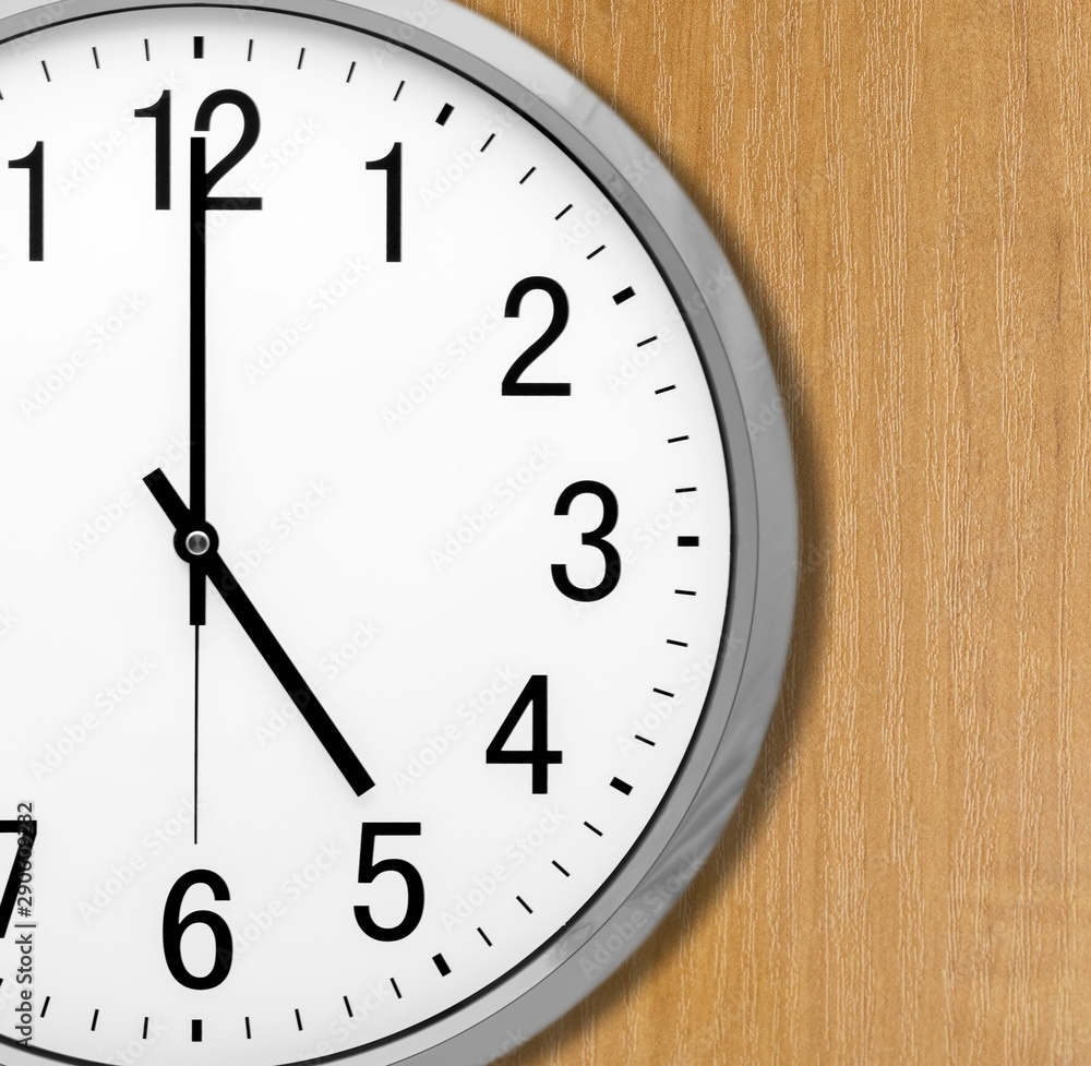 Silver round clock face on wooden desk