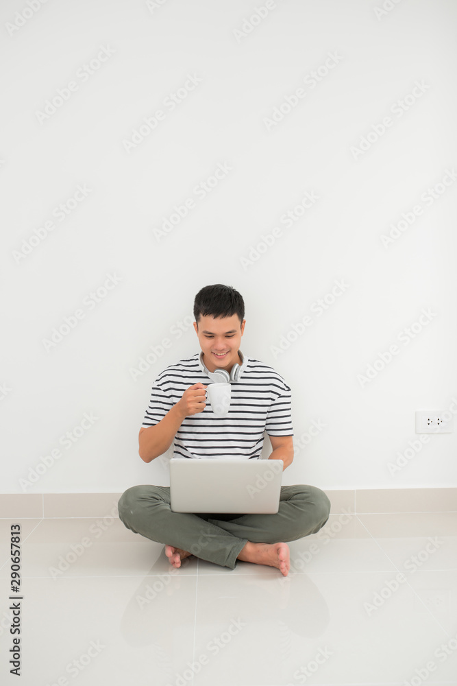 Businessman working on laptop computer sitting at home while drinking coffee.