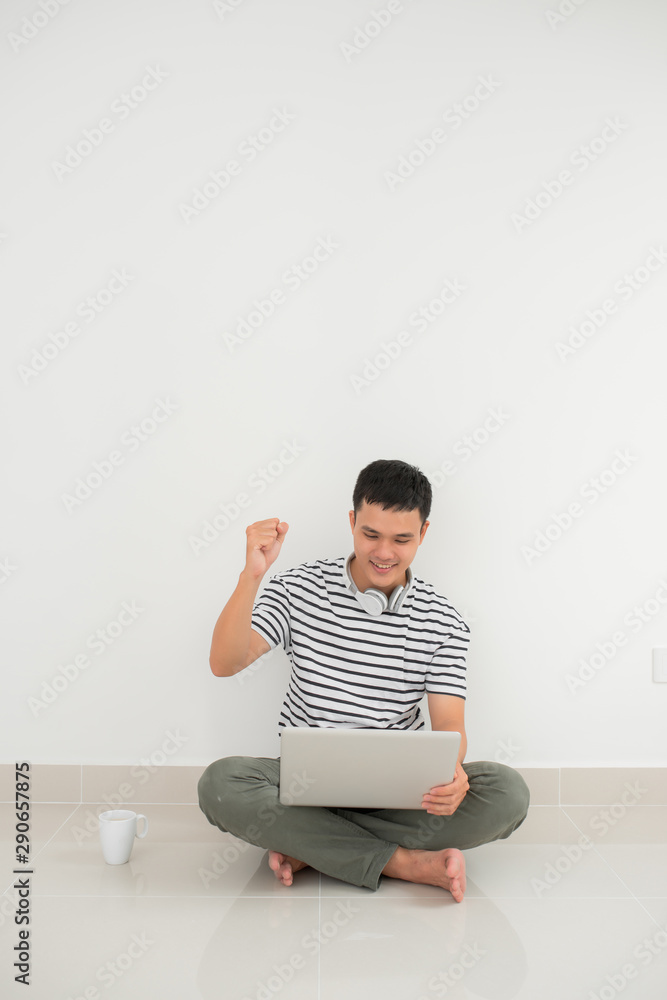 Portrait of a happy young man using laptop and celebrating success isolated over white background