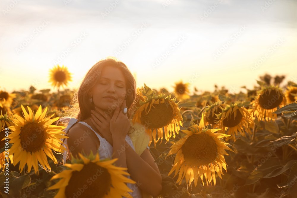 Beautiful young woman in sunflower field on summer day