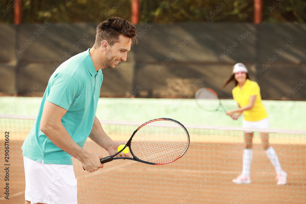 Young couple playing tennis on court