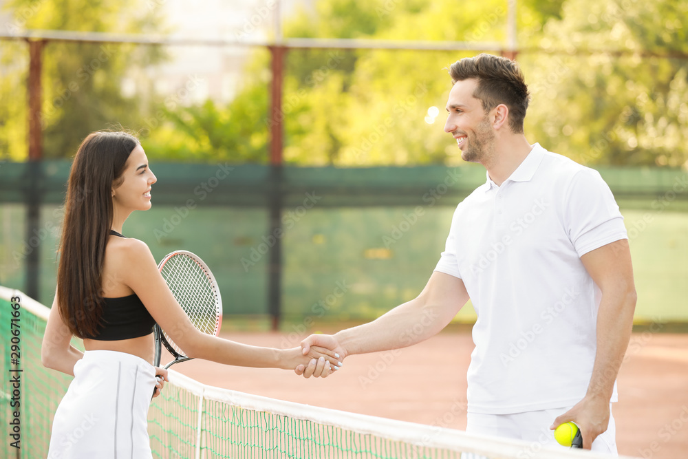 Young couple shaking hands on tennis court