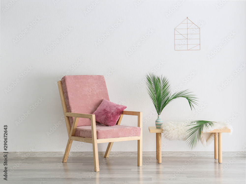 Armchair and table with floral decor near light wall