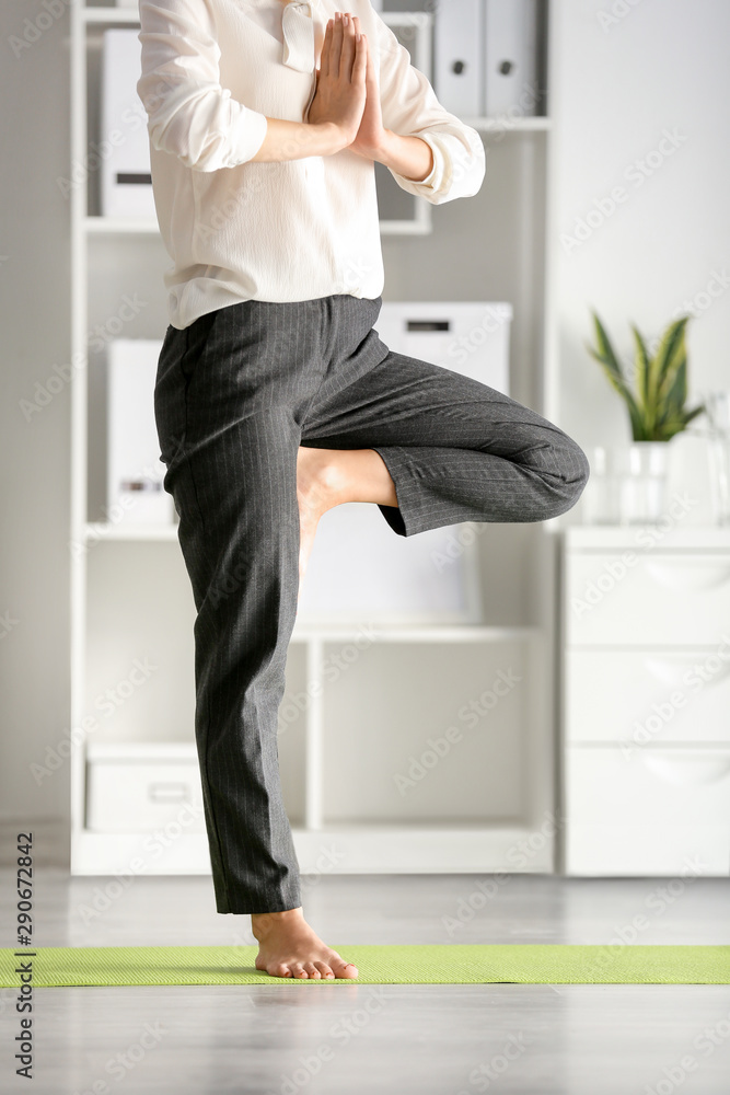 Young businesswoman practicing yoga in office