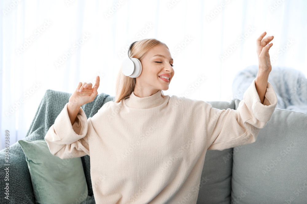 Beautiful young woman listening to music at home