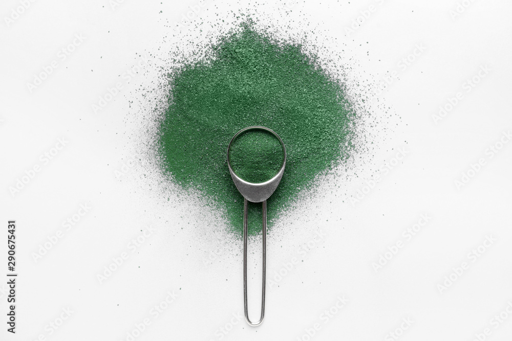 Scoop with spirulina powder on light background