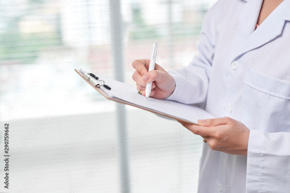 Cheerful medical doctor woman filling out prescription