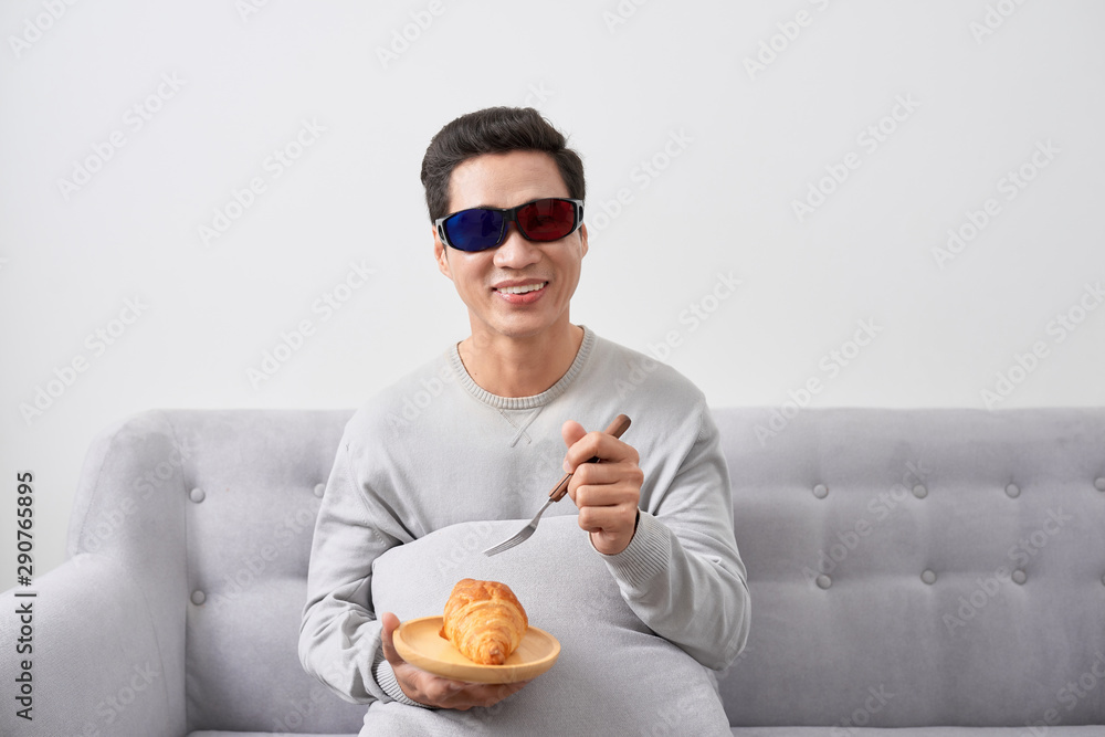 exciting young man watch three-dimensional LCD TV with eye glass in a living room