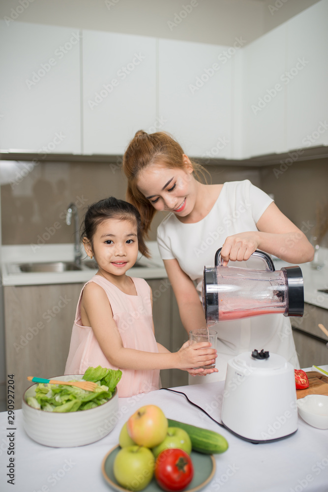 母亲和女儿正在搅拌机里准备沙拉菜单上有美味的奶昔和配料