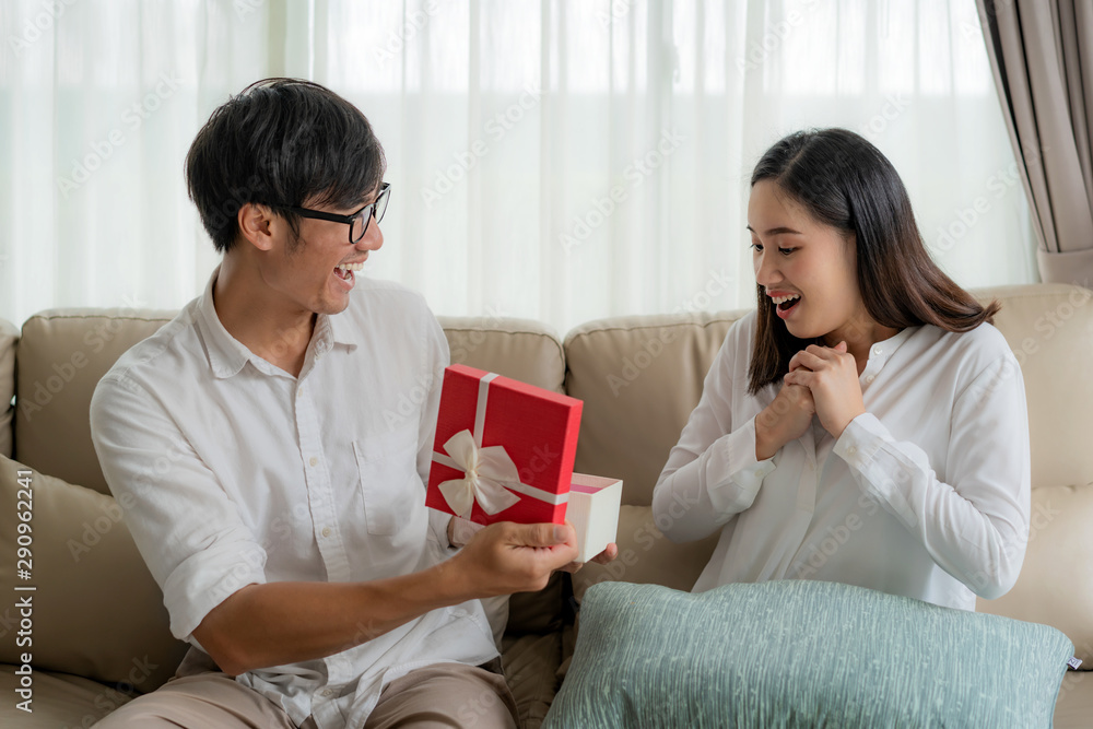 亚洲男人送给一个女人一个红色礼盒。她看着盒子里的礼物，在婚礼上大吃一惊。