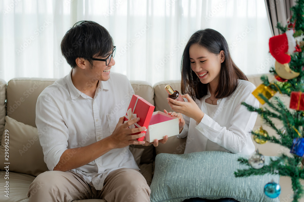 Asian man give the woman a red gift box in which there is a bottle of perfume. The woman was picked 