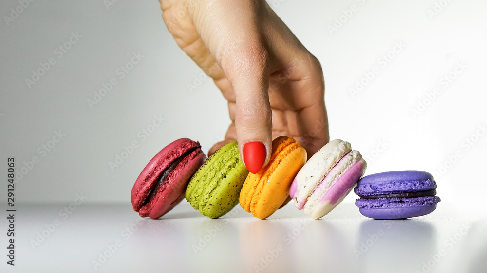 Eating macarons. Female hand holding macarons over  grey background