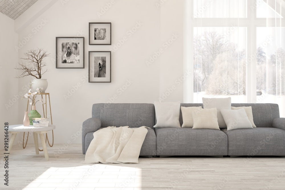 Stylish room in white color with sofa and winter landscape in window. Scandinavian interior design. 