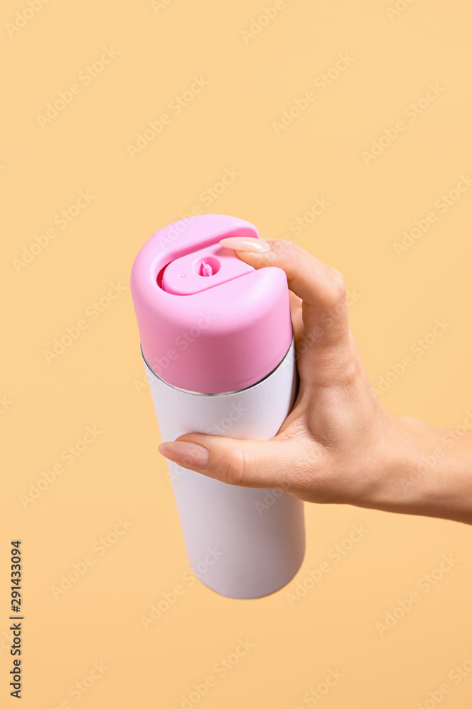 Female hand with bottle of air freshener on color background