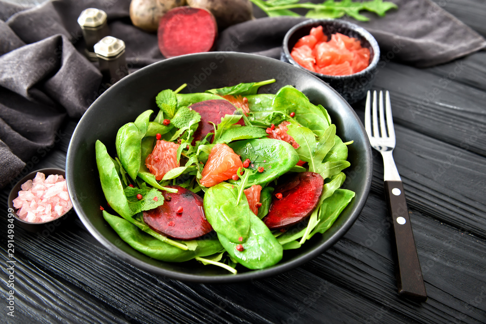 Plate with tasty salad on dark table