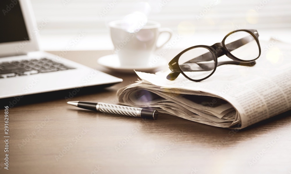 Newspaper with computer on table.