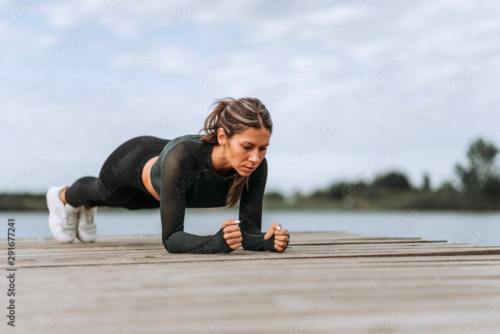 Female athlete doing plank exercise by the river.