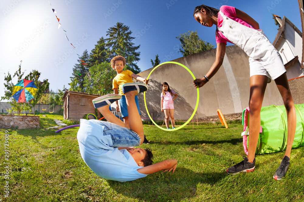 Boy roll on the grass after jumping through hoop