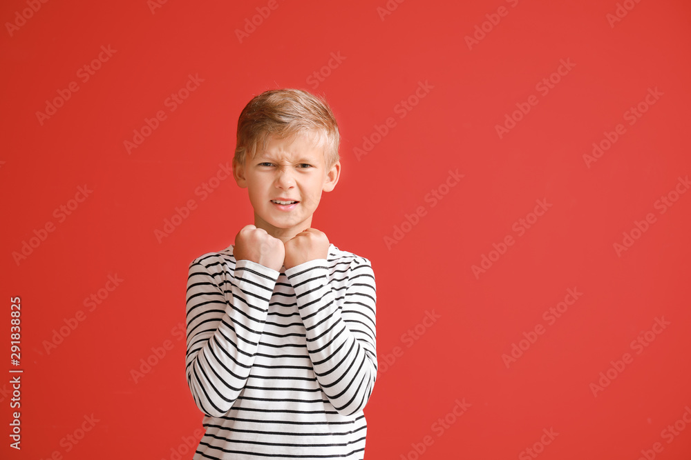 Portrait of angry little boy on color background