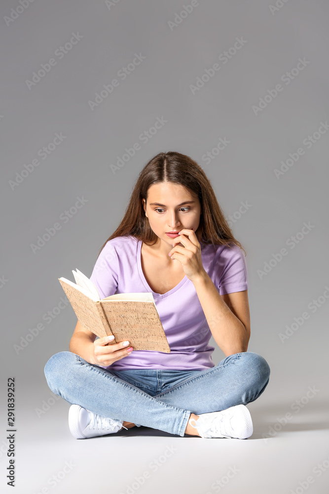 Young girl with book on grey background