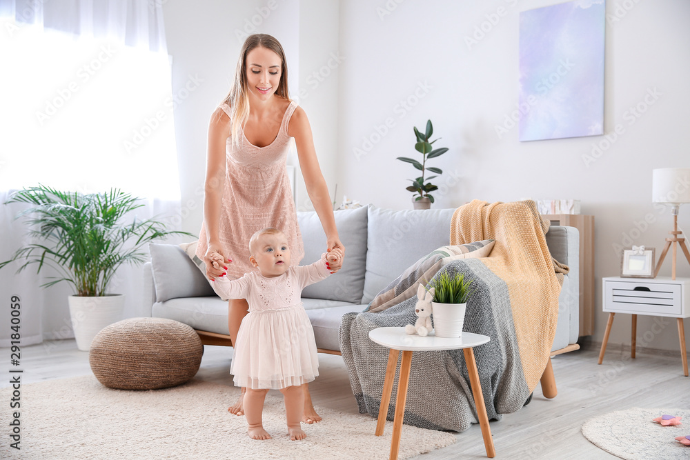 Mother teaching her little baby to walk at home