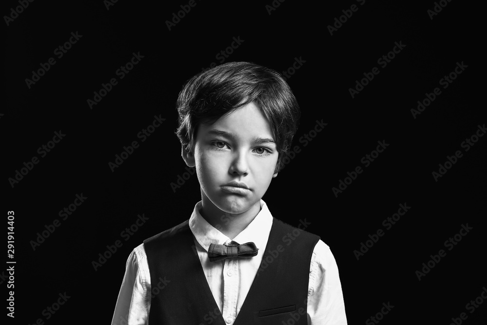 Black and white portrait of sad little boy on dark background