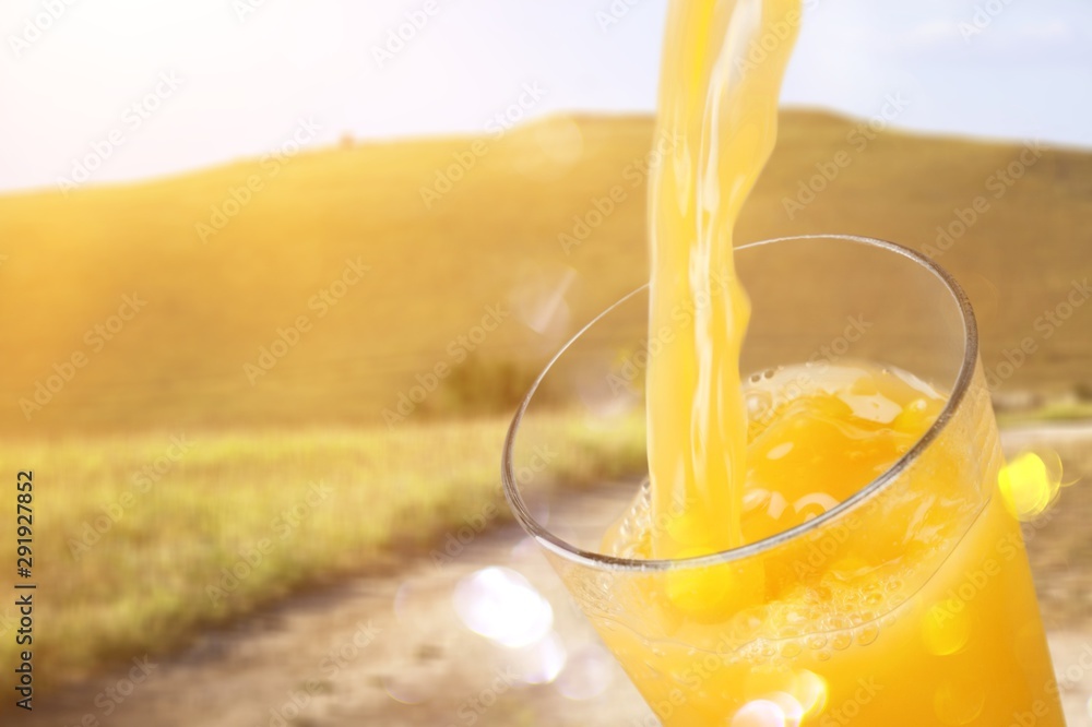 Orange juice glass on green blurred garden background, bokeh