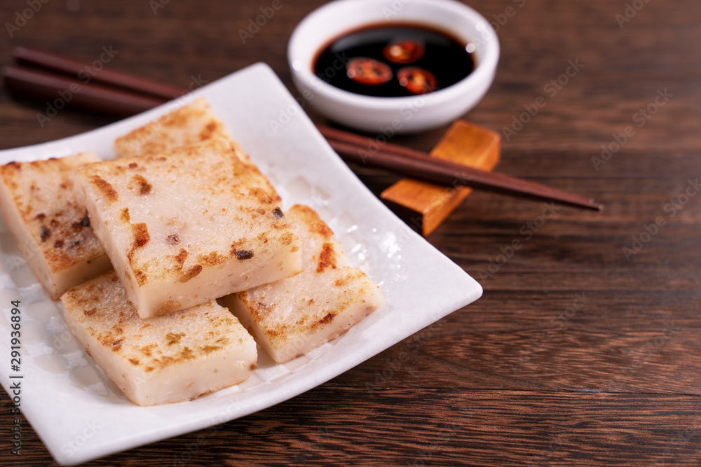 Delicious turnip cake, Chinese traditional local dish radish cake in restaurant with soy sauce and c