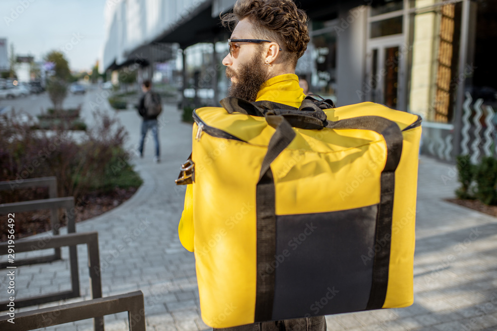 Delivery Man standing with yellow thermo backpack for food delivery with empty space to copy paste o