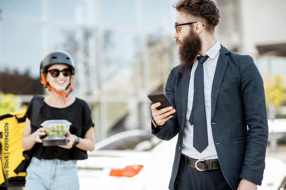 Office worker waiting for a courier, ordering with phone takeaway lunch from a restaurant. Fresh res