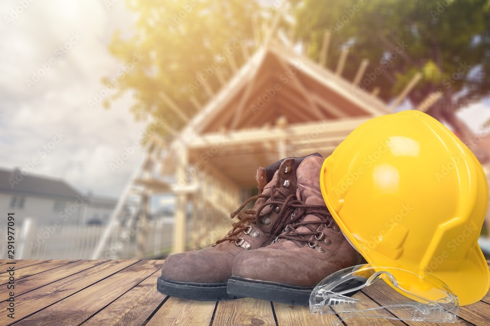 Yellow working hard hat, goggles and work boots on  background