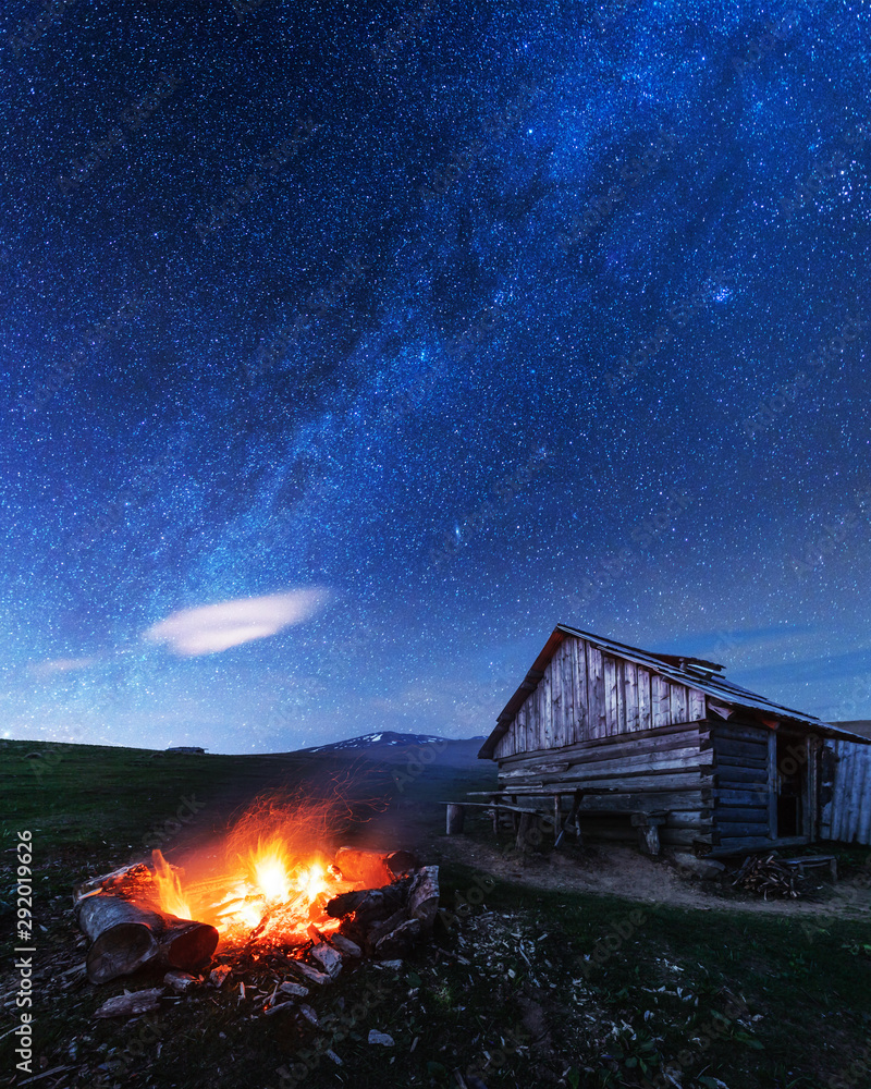 strarry夜空背景下老木屋附近的篝火