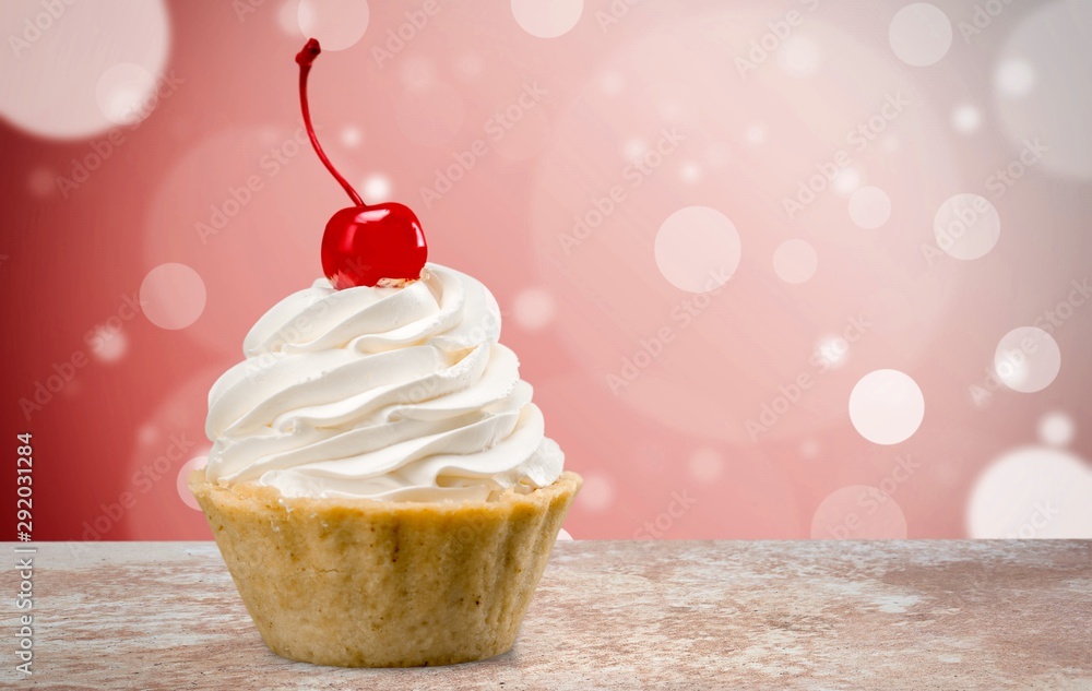 Cupcake with whipped cream and cherry isolated on background