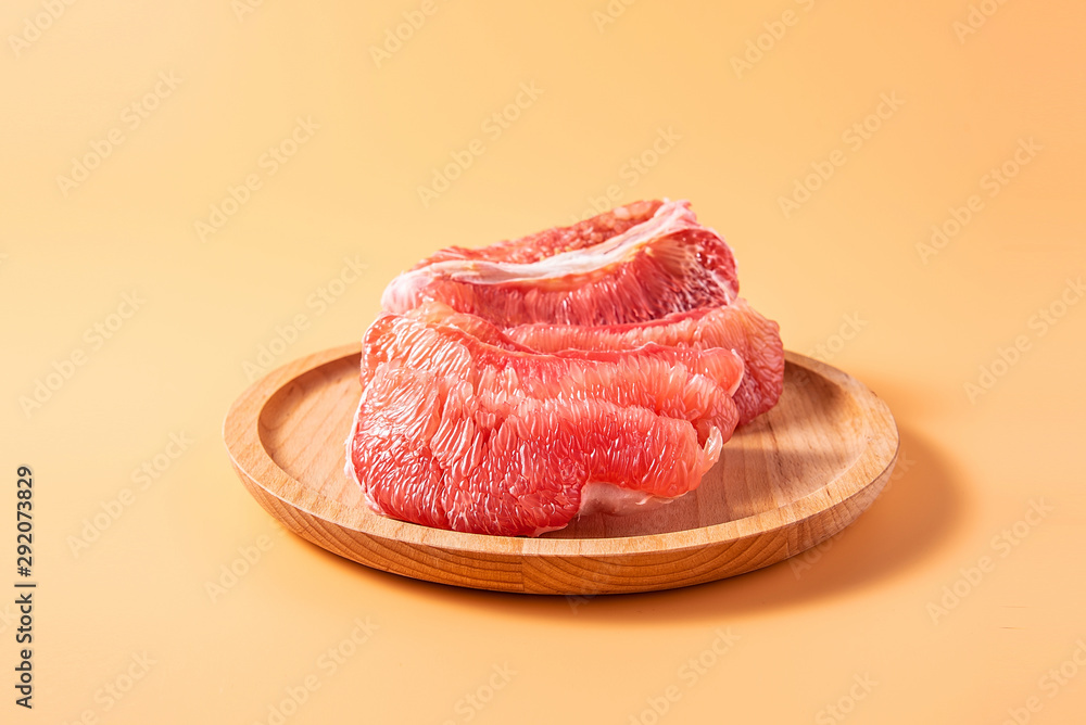 A plate of fresh red grapefruit meat on a yellow background