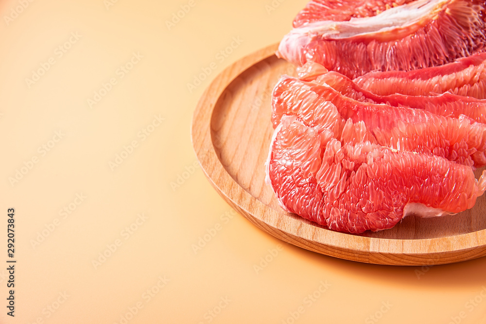 A plate of fresh red grapefruit meat on a yellow background