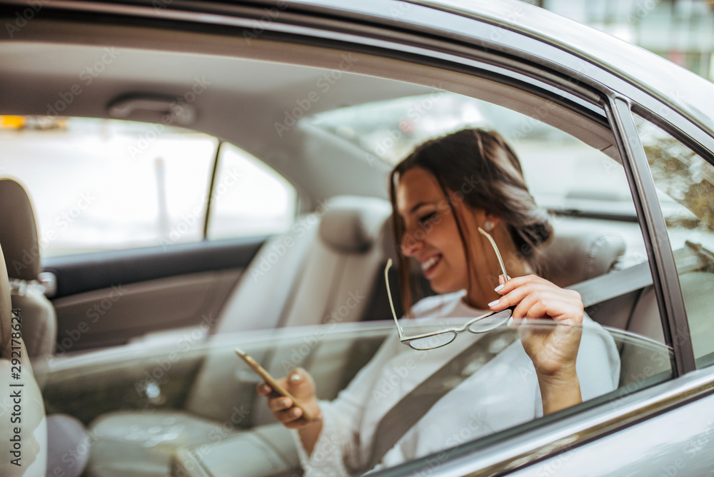 Cheerful business woman on the backseat of a car, copy space.