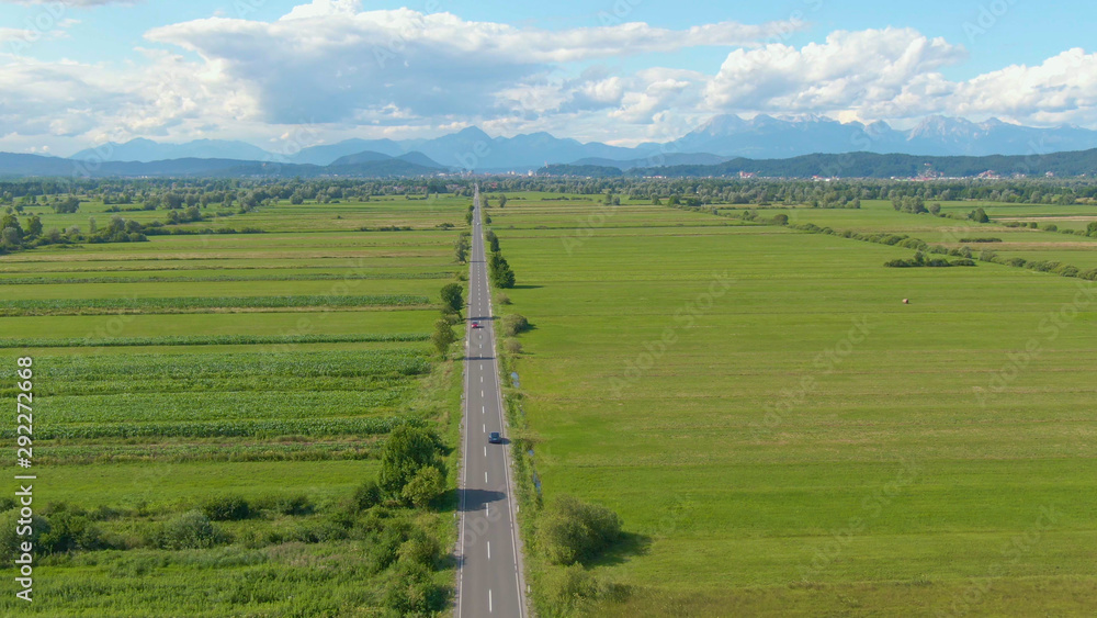 无人机：在一辆自动驾驶汽车后面飞行，沿着笔直的乡村道路行驶。