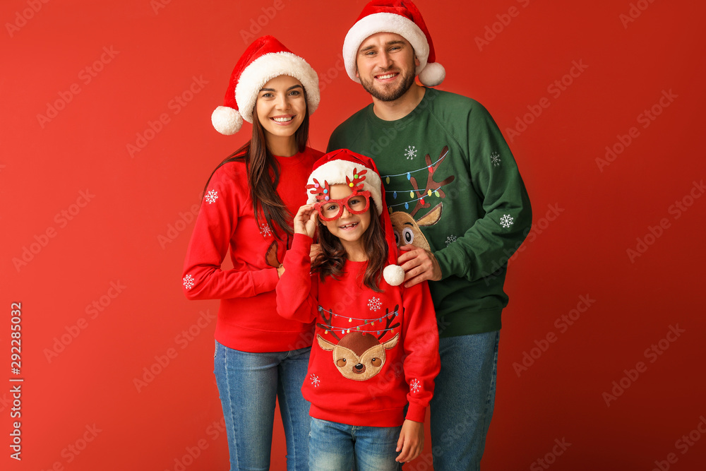 Happy family in Christmas sweaters and Santa hats on color background