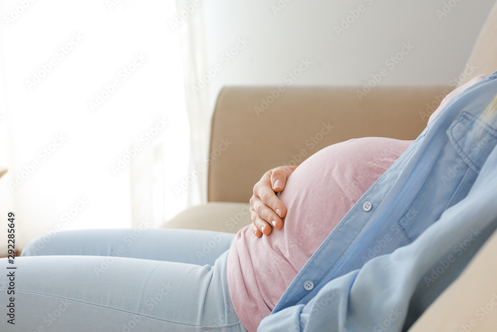 Beautiful pregnant woman sitting on sofa at home