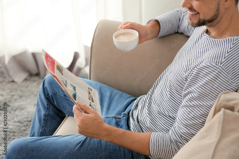 Man with newspaper and cup of coffee relaxing at home