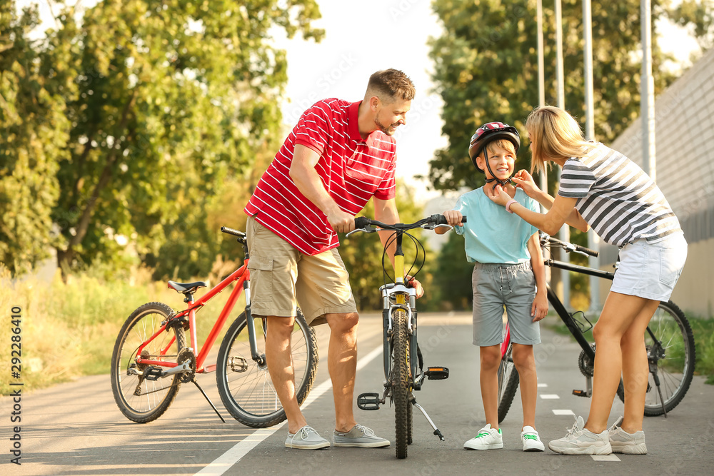 Parents teaching their son to ride bicycle outdoors