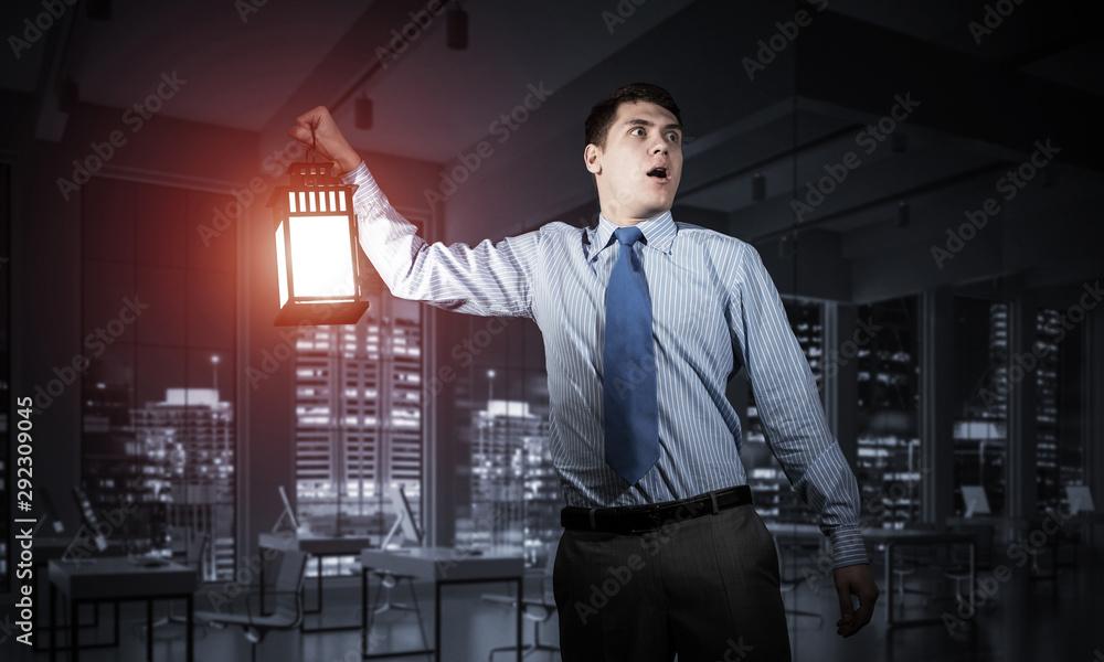 Scared businessman holding glowing lantern