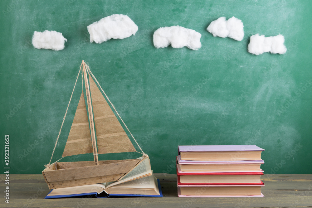 Education is a journey concept, toy boat and books on the chalkboard background, inspiration for a f