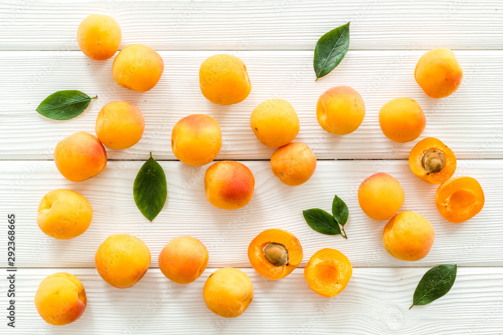 Apricots and leaves pattern on white wooden background top view